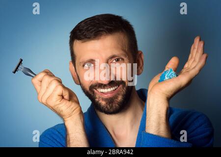 Mittleren Alters lächelnder bärtiger Mann hält in den Händen Rasur Creme und Rasiermesser. Stockfoto