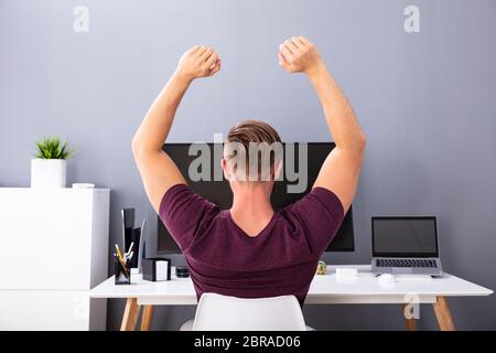 Ansicht der Rückseite des Geschäftsmann Sitzen auf Stuhl mit Arm im Amt angehoben Stockfoto
