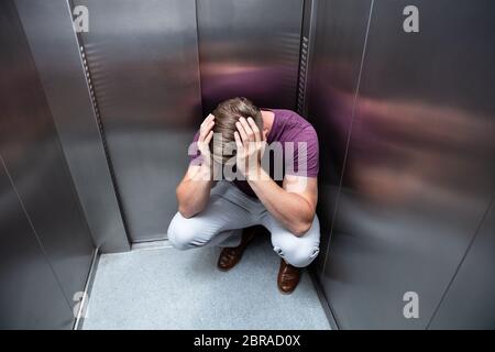 Besorgt man mit den Händen auf den Kopf im Aufzug Geduckt Stockfoto