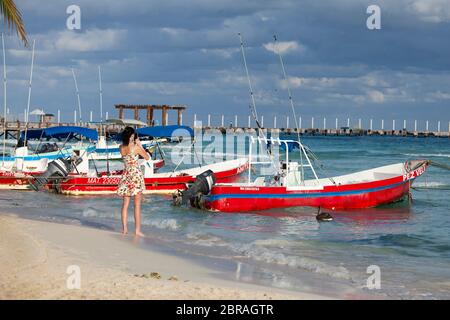 Eine junge Frau fotografiert bunte Boote in der Nähe der Docks von Playa del Carmen, Quintana Roo, Mexiko. Stockfoto