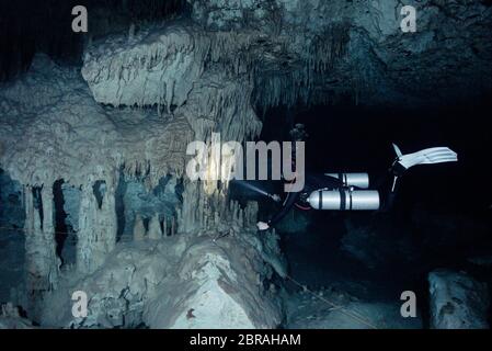 Sidemount Technical Diver schwimmt um einzigartige Kalksteinformationen im Cenote Dreamgate in Mexiko. Stockfoto