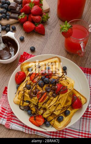 Belgische Waffeln mit Heidelbeeren, Erdbeeren mit Schokolade überzogen Stockfoto