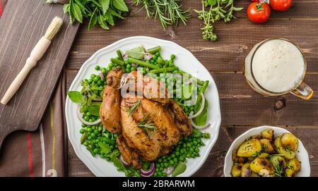 Gegrilltes Bio Bio Huhn, Bratkartoffeln, mit Frühling Gemüse und Kräutern, mit Bier Stockfoto