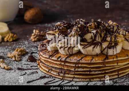 Rustikale Pfannkuchen mit Banane und Schokolade, gerösteten Nüssen an der Spitze Stockfoto