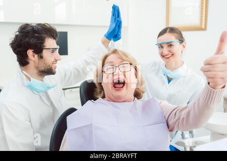 Zahnärzte und Patienten in der Chirurgie, die ein bisschen über die Spitze aufgeregt geben hohe fünf Stockfoto