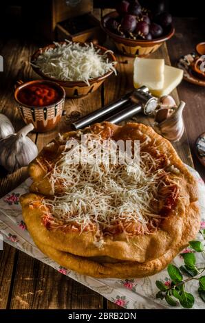 Traditionelle Langos sind ursprünglich ungarische Pfannkuchen aus Hefeteig, gekrönt mit Käse, Knoblauch und Tomatenketchup. Dieses Gericht wird verkauft bei Stockfoto