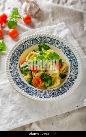 Tortellini gefüllt mit Fleisch mit gerösteten Tomaten und Basilikum, Olivenöl Stockfoto