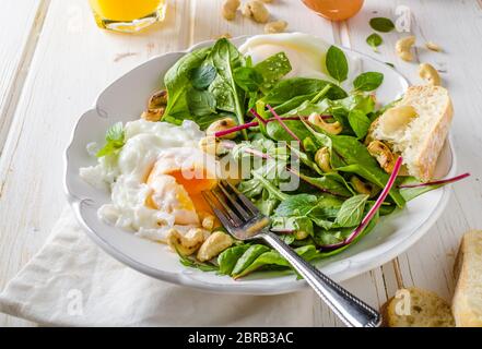 Lamm-Salat mit gebratenem Ei, frisch gepresster Orangensaft und gerösteten Nüssen und Baguette Stockfoto