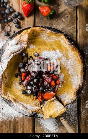 Holländische Baby-Pfannkuchen mit Beeren und Schokolade, gebacken im Ofen auf Eisenpfanne, besten Pfannkuchen immer!!! Stockfoto