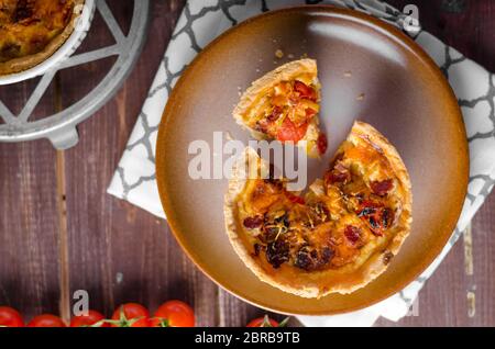 Mini-Quiche mit Würstchen, Mini-Tomaten und Kräutern Stockfoto