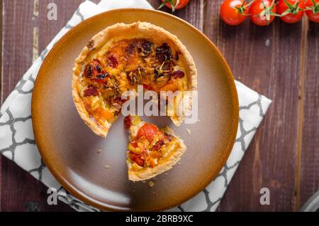 Mini-Quiche mit Würstchen, Mini-Tomaten und Kräutern Stockfoto