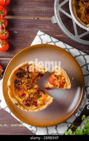 Mini-Quiche mit Würstchen, Mini-Tomaten und Kräutern Stockfoto