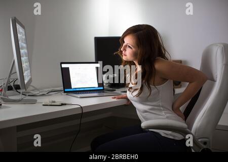 Frau, die Computer in einem Home Office - Form leiden, Schmerzen im unteren Rücken Stockfoto