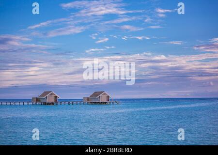 Sonnenuntergang Himmel und Reflexion über das ruhige Meer, Malediven Strand Landschaft von Luxus über Wasser Bungalows. Exotische Landschaft von Sommer und Urlaub Stockfoto