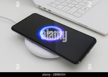 Aufladen des Smartphones über ein kabelloses Ladegerät Stockfoto