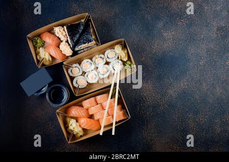 Leckere Sushi-Brötchen in Einweg-Kraftpapier-Boxen, Saucen, Essstäbchen. Sushi zum Mitnehmen oder Anliefern Stockfoto
