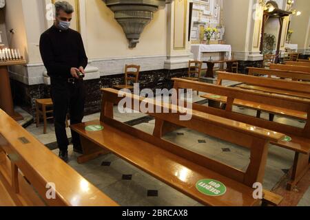 Der Pfarrer Enzo berechnet mit einem Lasermeter die genaue Entfernung zwischen den Gläubigen in den Kirchenbänken. Stockfoto