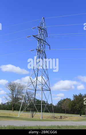 Power Line Tower mit Kabeln und Drähten, mit blauem Himmel und weißen Wolken, die hell und bunt in Kansas ist. Stockfoto