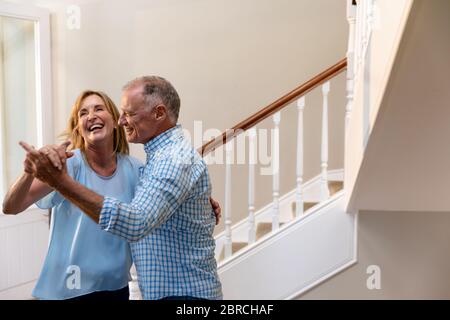 Kaukasisches Paar, das Spaß am Tanzen und Lächeln auf dem Flur hat Stockfoto