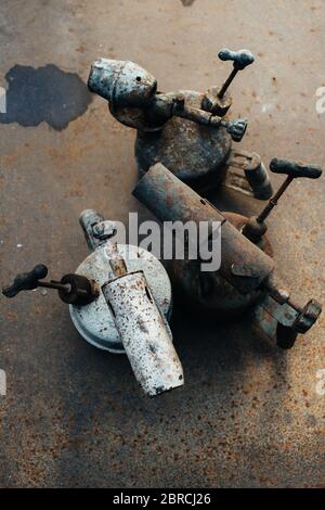 Alte rostige Gasbrenner steht auf einem rostigen Eisenblech. Metallschrott. Nahaufnahme. Stockfoto