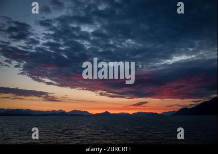 Kleine Schiffsrundfahrten in Stephens Passage, Südost-Alaska, USA bieten Touristen wunderschöne landschaftliche Aussichten wie diesen feurigen Sonnenuntergang über der Inside Passage. Stockfoto