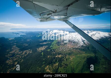 Die Rundflüge zwischen Juneau und Gustavus im Südosten Alaskas, USA, bieten atemberaubende Luftaufnahmen von einem Wasserflugzeug aus, das schneebedeckte Berge und Meerwasser umfasst Stockfoto