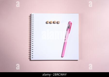 Geöffnetes Buch und Stift und Holzsteine mit Schild auf dem rosa Hintergrund. Platz für Text. Top im Blick. Stockfoto