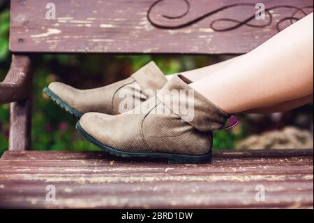 Damenbeine in Lederstiefeln. Frau, die im Park ruht Stockfoto