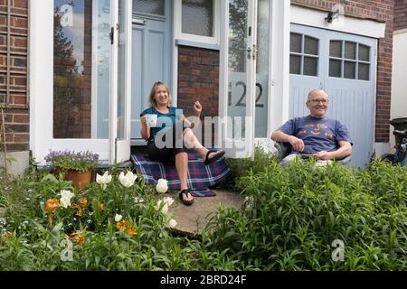 Während das Land die Blockade des Coronavirus der britischen Regierung fortsetzt und die sozialen Abgrenzung noch in Kraft ist, sitzt ein Paar der Mittelklasse am 17. Mai 2020 auf der Veranda im Vorgarten vor ihrem Haus in Herne Hill, Südlondon, in London, England. Stockfoto