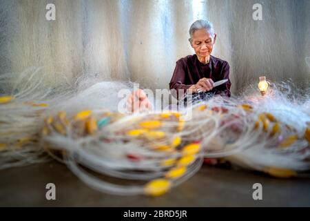 Vinh Thanh Sea, Hue City, Thua Thien Hue Province, Vietnam - 9. Mai 2020: Bild einer älteren Frau, die ein Fischernetz anstellt Stockfoto