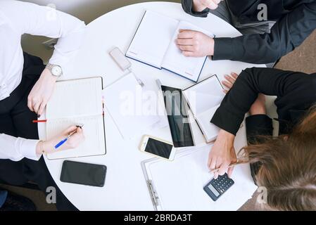 Business-Team bei der Sitzung. Mitarbeiter schreiben in einem Notizbuch Plan und Ideen. Blick von oben. Flatlay Stockfoto