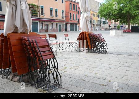 Tische und Stühle eines Cafés im Freien ohne Touristen aufgrund der Quarantänesperre durch Corona Virus in Venedig in Italien Stockfoto