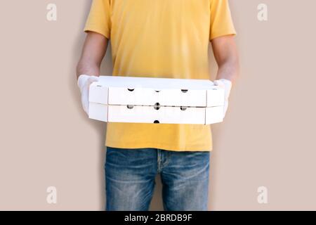 Mann aus dem Lieferservice in Schutzmaske und Handschuhe halten Pizza-Boxen. Stockfoto