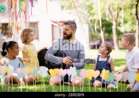 Mann mit kleinen Kindern im Sommer im Garten auf dem Boden sitzend, spielend. Stockfoto