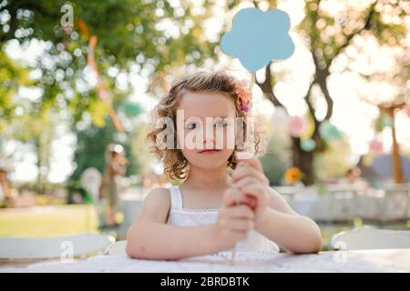 Kleines Mädchen im Garten im Sommer sitzen, Geburtstagsfeier Konzept. Stockfoto