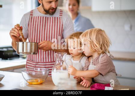 Junge Familie mit zwei kleinen Kindern im Haus in der Küche, Kochen. Stockfoto