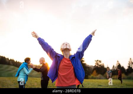 Ein Porträt einer jungen Frau mit einer großen Gruppe von Menschen, die in der Natur Sport treiben. Stockfoto