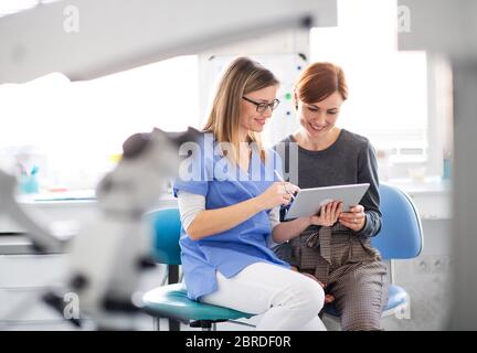 Ein Zahnarzt im Gespräch mit einer Frau in der Zahnarztpraxis, eine zahnärztliche Kontrolle. Stockfoto