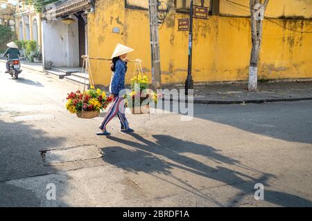 Alte Stadt Hoi an, Provinz Quang Nam, Vietnam - 10. Mai 2020: Foto einer Frau, die Blumen auf einem Bambusrahmen in der alten Stadt Hoi an verkauft, Q Stockfoto