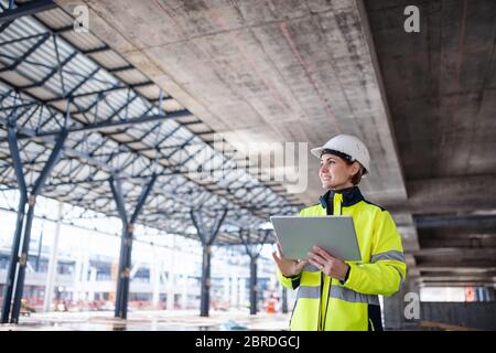 Eine Ingenieurin mit Tablet steht auf der Baustelle und arbeitet. Stockfoto