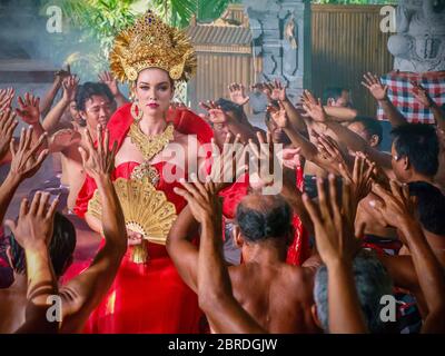 Ubud, Bali - 28. Juli 2016. Die traditionelle kunstvolle balinesische Frauen zeremoniellen Kopfschmuck und Schmuck, in der Kulisse eines männlichen Kecak Tanz. Stockfoto