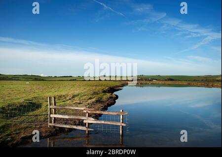 Der Fluss Cuckmere schlängelt sich sanft durch Auen in der Nähe des Meeres bei Cuckmere Haven in Sussex, England Stockfoto