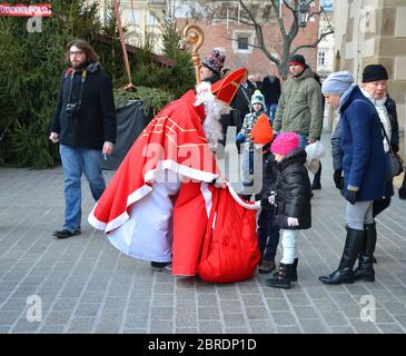 KRAKAU, POLEN - 4. DEZEMBER 2016: Weihnachtsmann schenkt Kindern auf dem Weihnachtsmarkt Geschenke.der jährliche weihnachtsmarkt auf dem Marktplatz ist ein Pop Stockfoto