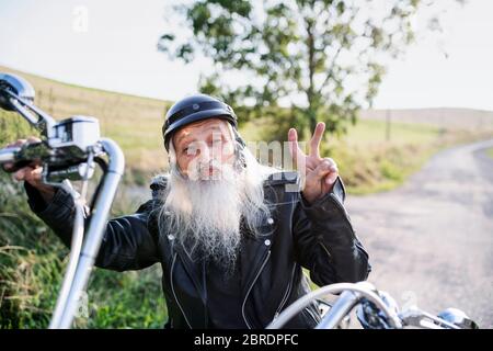 Ein älterer Mann, der mit dem Motorrad auf dem Land unterwegs ist. Stockfoto