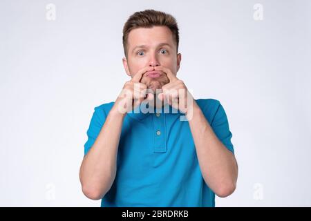 Fröhlicher junger Mann, der vorgibt, er habe einen Schnurrbart und mache eine Geste aus dem Finger. Studioaufnahme Stockfoto