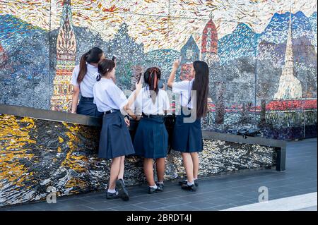 Eine Gruppe thailändischer Universitätsstudenten nimmt sich einen Moment Zeit, um Make-up zu machen, zu plaudern und Telefone auf dem Balkon der Iconsiam Shopping Mall, Bangkok, zu betrachten. Stockfoto