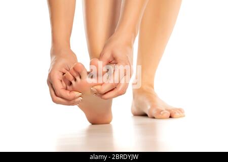 Frau massiert ihren schmerzhaften Fuß auf weißem Hintergrund Stockfoto