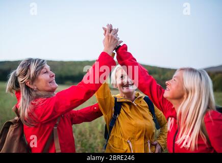 Ältere Frauen auf Spaziergang im Freien in der Natur in der Dämmerung, geben hohe fünf. Stockfoto