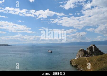 Blick auf den Schamanen-Felsen auf der Insel Olchon mit einem Kreuzfahrtschiff auf dem Wasser in der Nähe (Baikalsee, Russland) Stockfoto