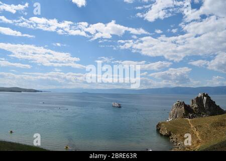 Blick auf den Schamanen-Felsen auf der Insel Olchon mit einem Kreuzfahrtschiff auf dem Wasser in der Nähe (Baikalsee, Russland) Stockfoto